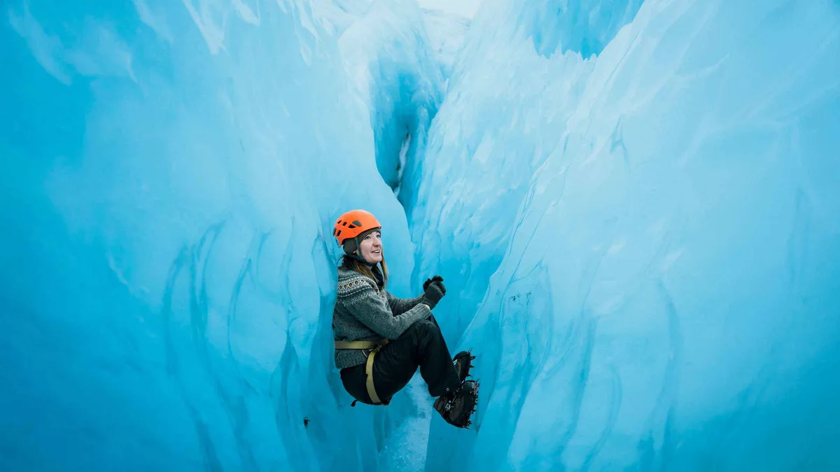 Walkers between towering crevasse walls in the Blue Ice Maze on Falljökull, below the Vatnajökull ice caves at Skaftafell, Iceland